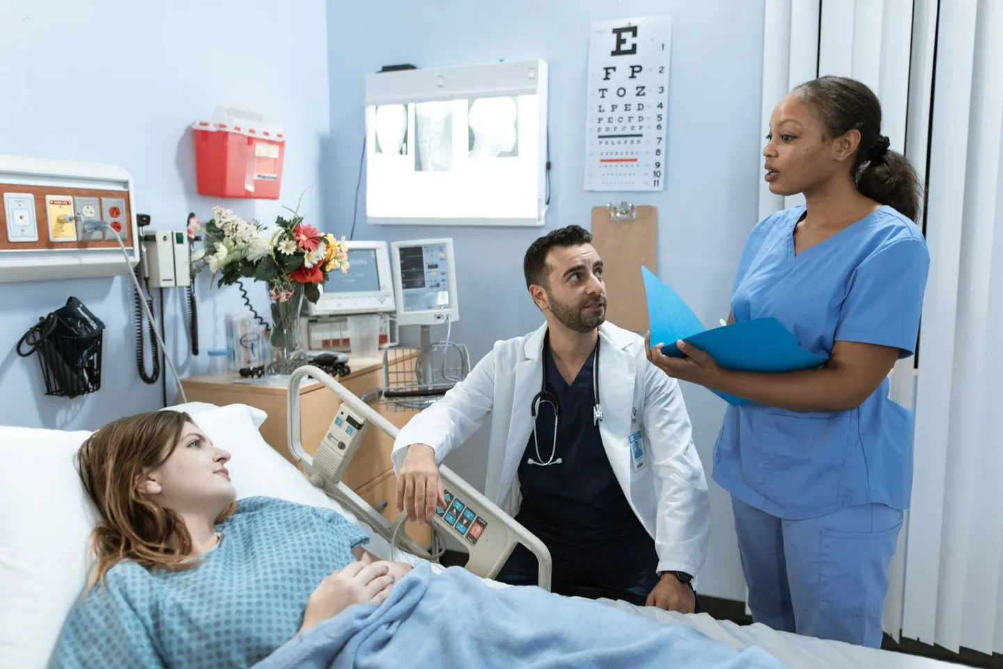 A physician and nurse consulting with a patient at the bedside in a clinic room, the kind of visit that becomes a five-star Google review when the practice asks the right way