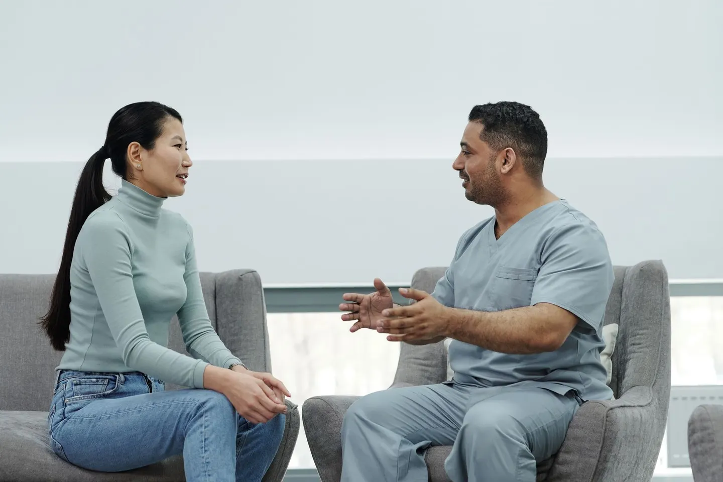 Clinician in scrubs talking through healthcare marketing options with a patient in a modern clinic lounge